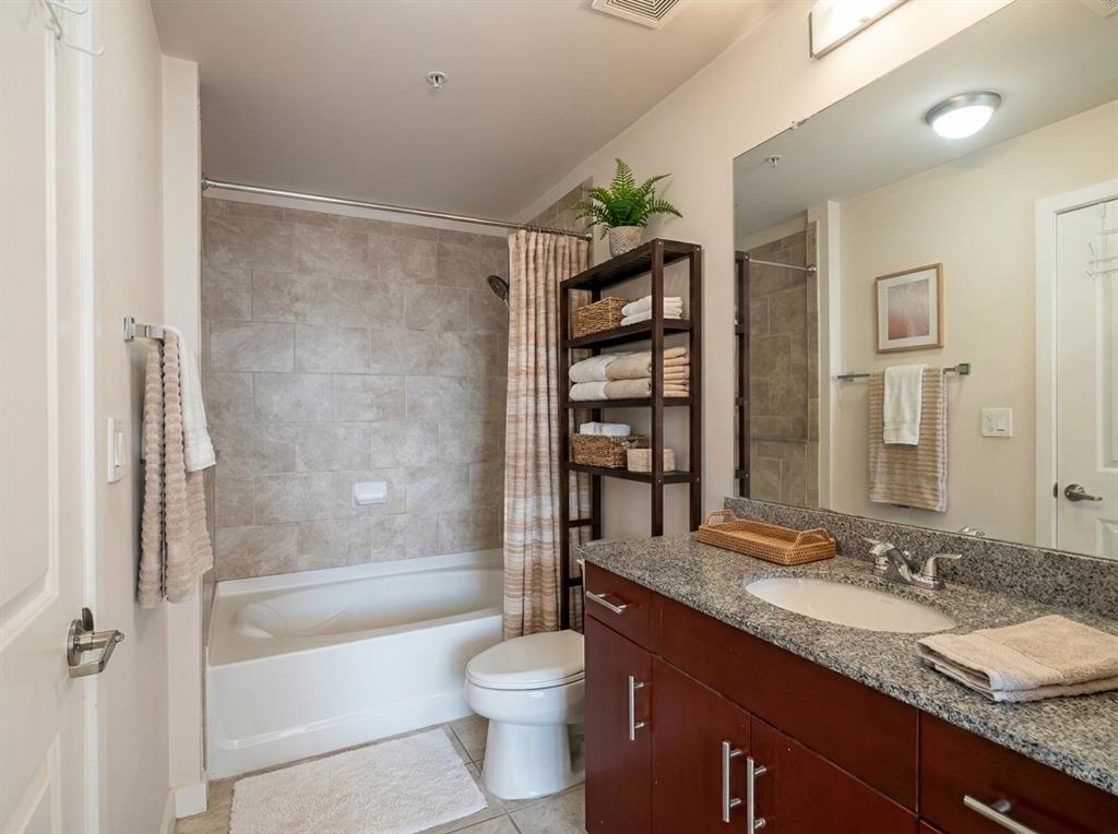 Full bathroom with granite vanity and tiled tub surround
